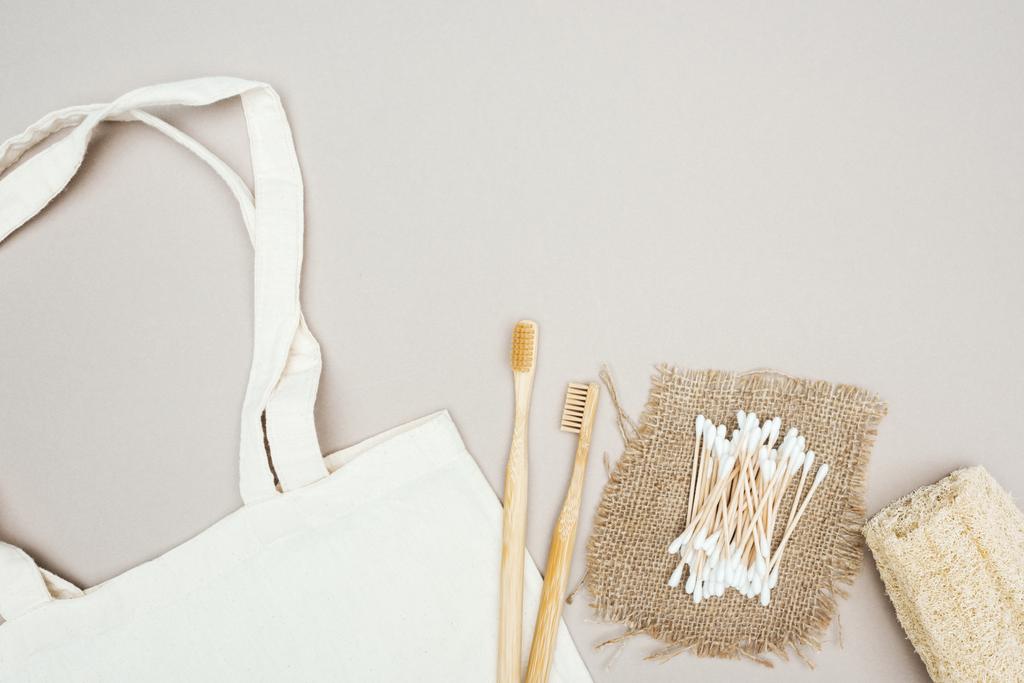 fa fogkefék, szerves luffa, vattatampon, zsákkendővel és fehér pamut táska szürke háttérrel - Fotó, kép