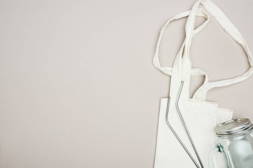 vista superior de la bolsa de algodón blanco, tarro de vidrio y paja de acero inoxidable reutilizable sobre fondo gris
 - Foto, imagen