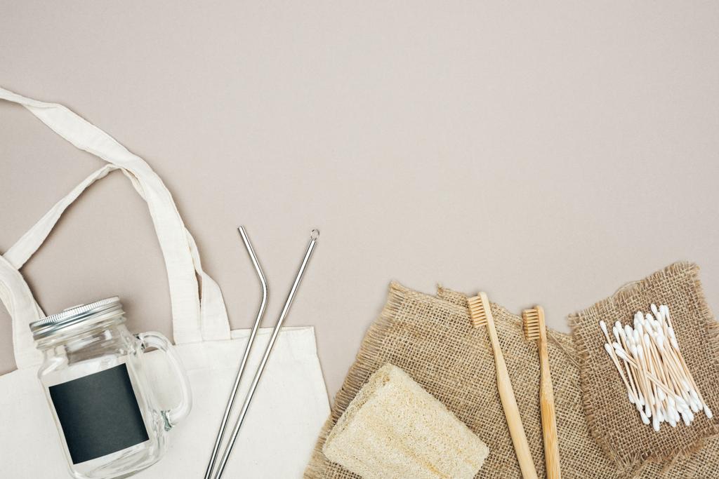 bamboo toothbrushes, organic loofah, cotton swabs, brown sackcloth, cotton bag with jar and stainless steel straws on grey background - Photo, Image