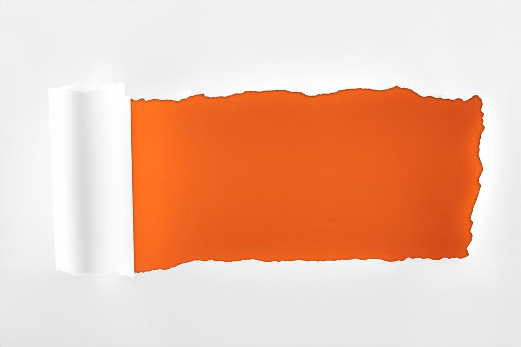 rongyos fehér papír, hengerelt széle mély narancssárga háttérrel  - Fotó, kép