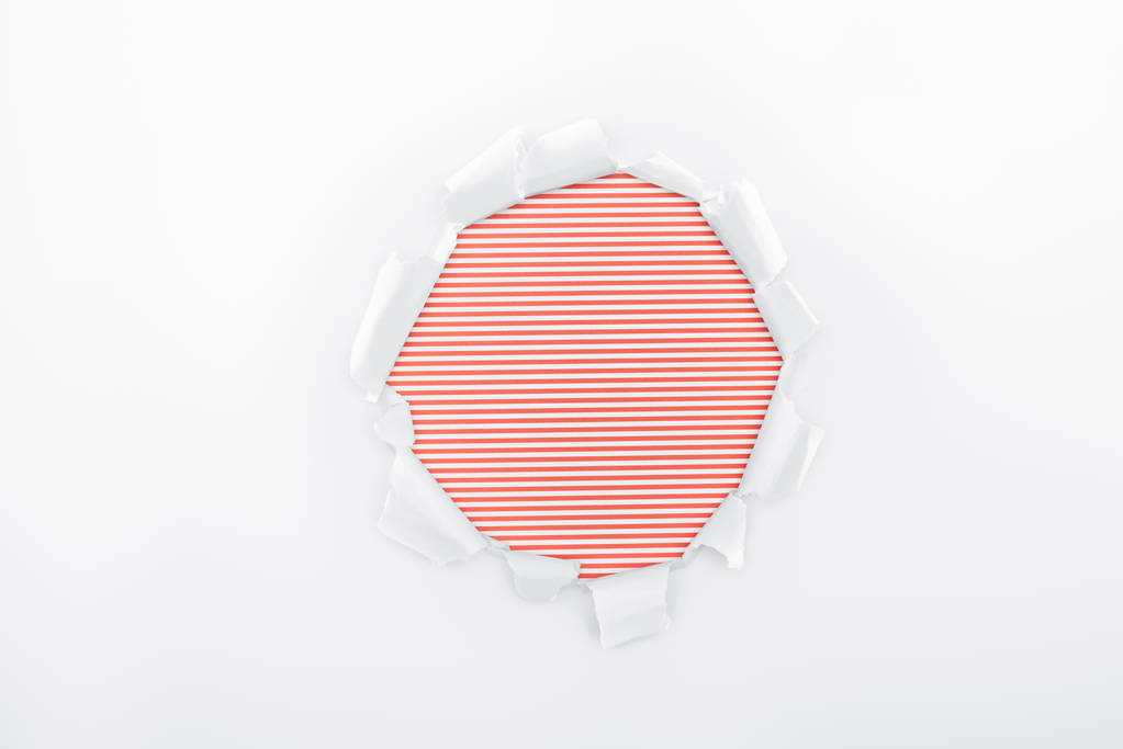 roztrhaný otvor v bílém papíře s texturou na červeném proužkované pozadí  - Fotografie, Obrázek