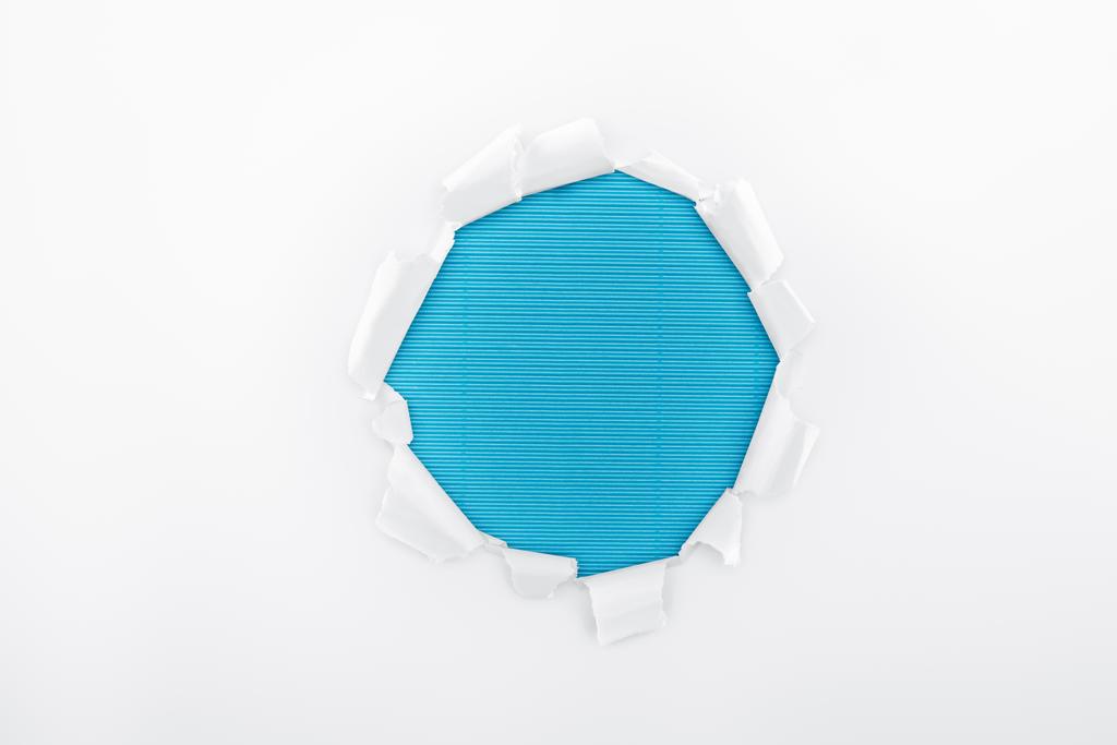 roztržený otvor v bílém texturovaném papíře na modrém proužkované pozadí  - Fotografie, Obrázek