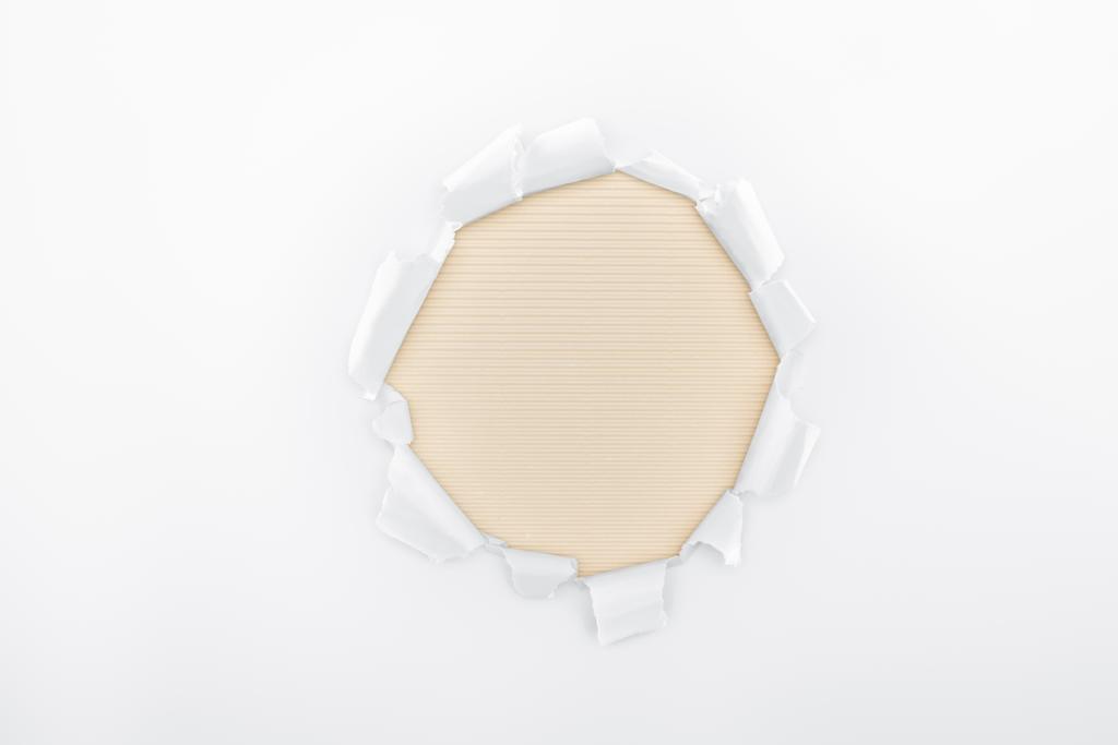 agujero rasgado en papel texturizado blanco sobre fondo rayado beige
  - Foto, imagen