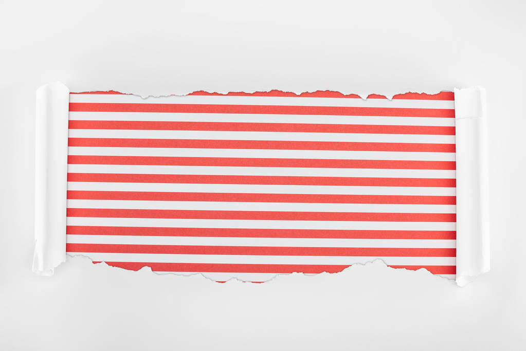 赤い縞模様の背景にカールエッジを持つ不規則なテクスチャの白い紙  - 写真・画像