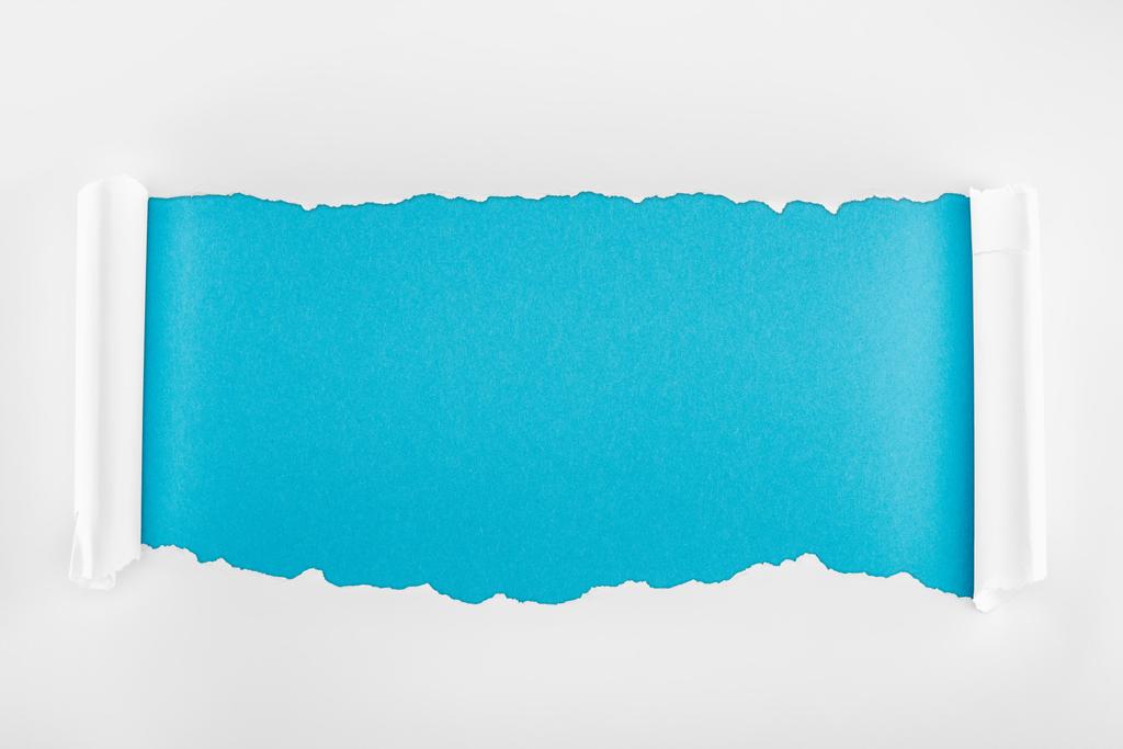 geript wit papier met krul randen op blauwe achtergrond  - Foto, afbeelding