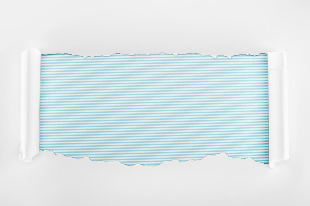 roztrhaný bílý texturované papír s okraji kudrlinkou na modrém proužkované pozadí  - Fotografie, Obrázek