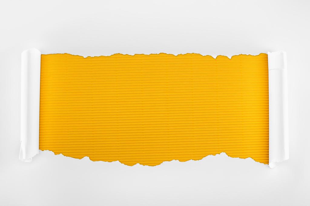zerrissenes weißes strukturiertes Papier mit Lockenrändern auf gelb gestreiftem Hintergrund  - Foto, Bild