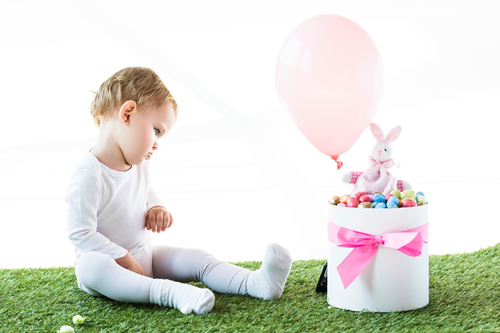 mignon bébé assis près de la boîte avec des œufs d'Estern, lapin décoratif et ballon à air isolé sur blanc
 - Photo, image