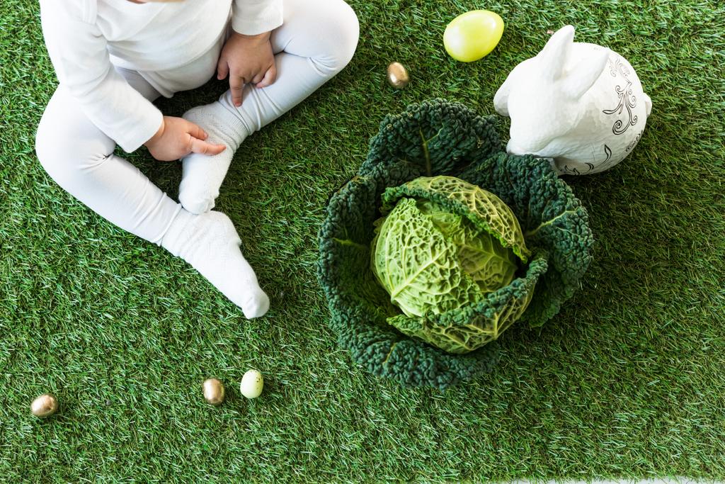 Paskalya yumurtaları, Dekoratif tavşan ve Savoy lahana yakın yeşil çim üzerinde oturan çocuk kısmi görünümü - Fotoğraf, Görsel