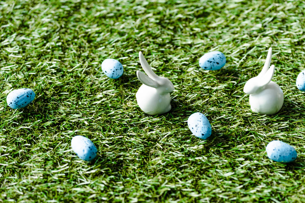 decorative rabbits and blue quail eggs on green grass surface - Photo, Image