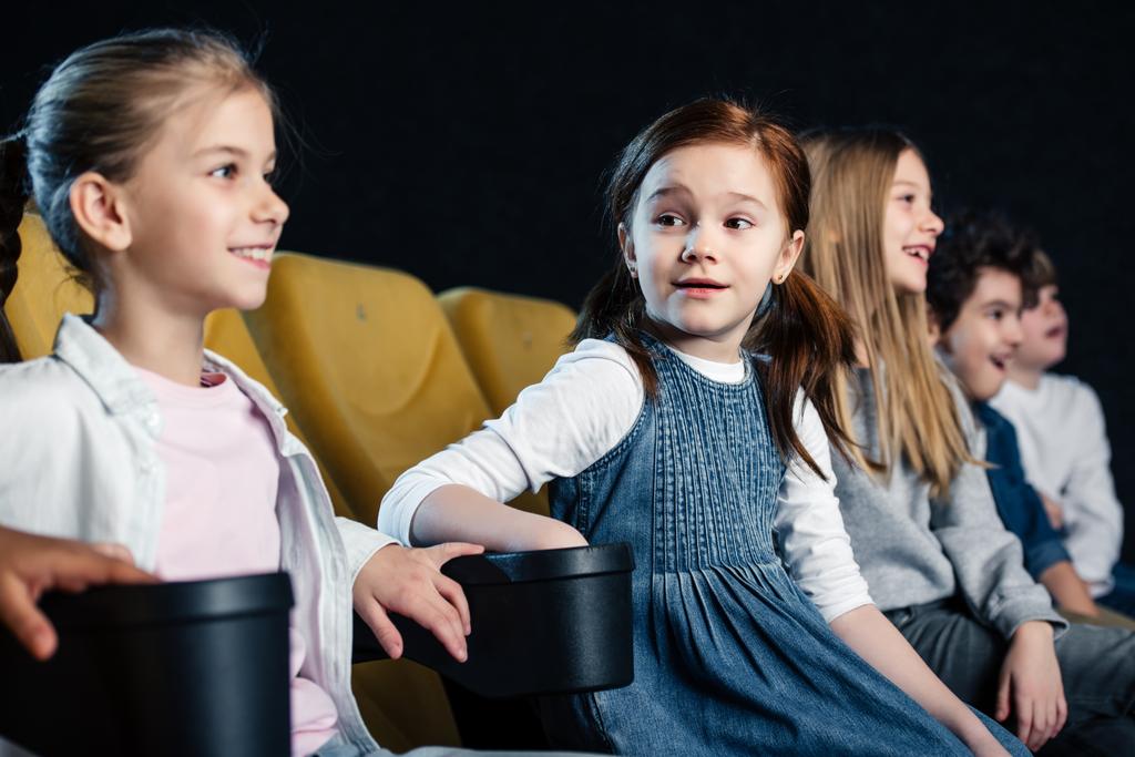 amigos multiculturales felices sentados en el cine y viendo películas juntos
 - Foto, Imagen