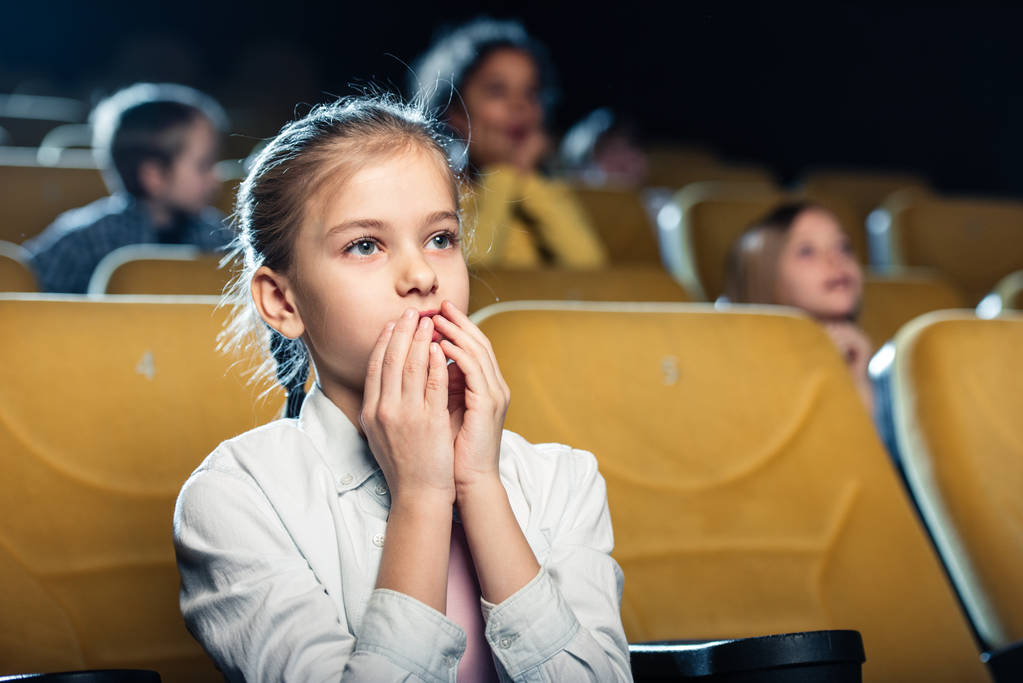 lindo niño preocupado viendo película en el cine junto con amigos multiculturales
 - Foto, Imagen
