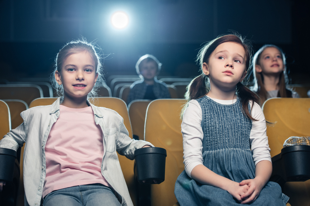 cute children sitting in cinema together with friends and watching movie - Photo, Image