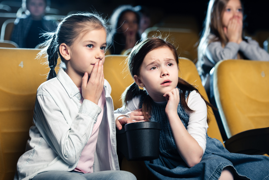 обеспокоенные дети смотрят кино в кино вместе с мультикультурными друзьями
 - Фото, изображение