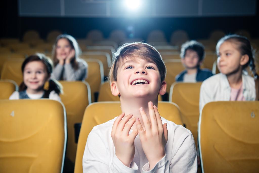 улыбающийся эмоциональный мальчик смотрит кино вместе с мультикультурными друзьями
 - Фото, изображение