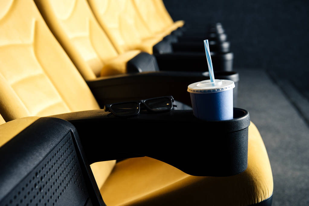foyer sélectif de sièges de cinéma orange avec tasse jetable dans le porte-gobelet
  - Photo, image