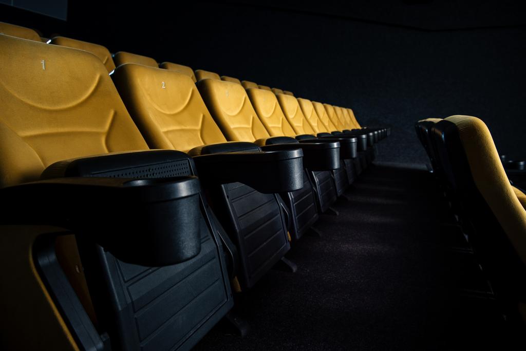 selective focus of orange seats with cup holders in cinema hall - Photo, Image