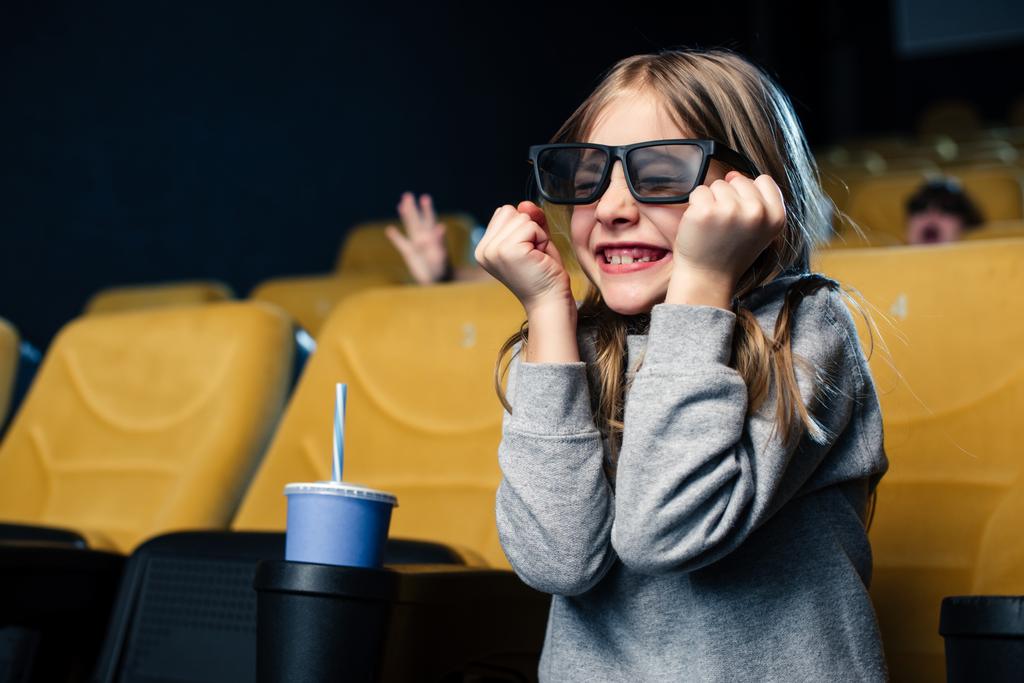 емоційна дитина в 3d окулярах дивиться фільм, сидячи біля паперової чашки
 - Фото, зображення