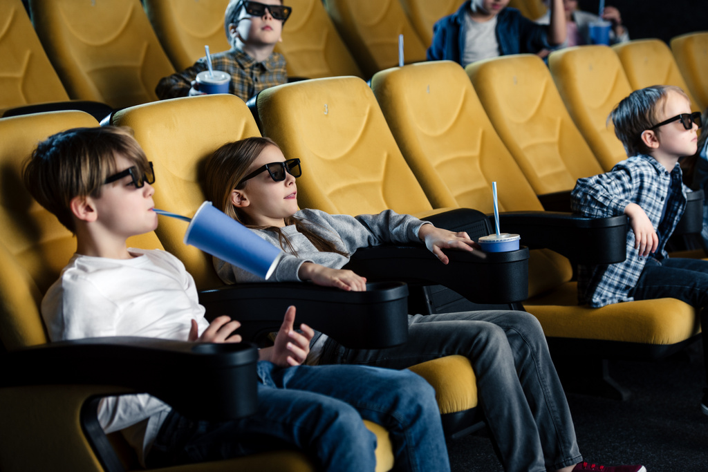 ystävät 3D-lasit katsomassa elokuvaa elokuvassa ja pitämällä paperimukeja
 - Valokuva, kuva