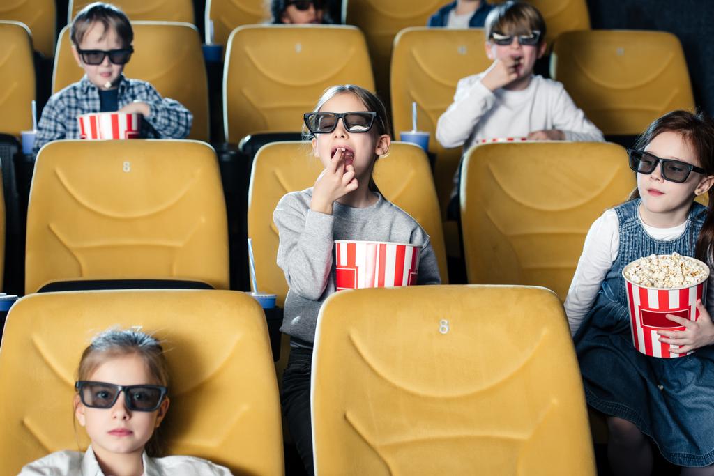 мультикультурные друзья смотрят кино в кино и едят попкорн
 - Фото, изображение