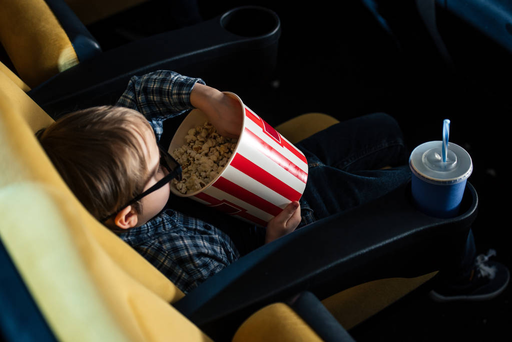 bovenaanzicht van schattige jongen in 3d bril popcorn eten in de bioscoop - Foto, afbeelding