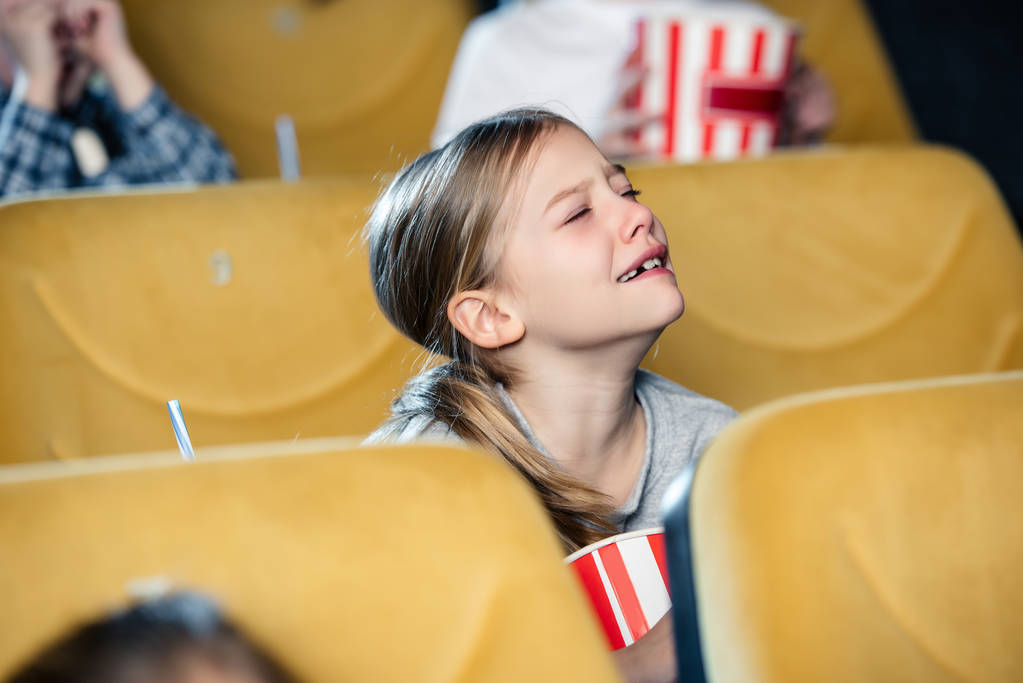 schattig boos kind huilen terwijl het letten van film in de bioscoop - Foto, afbeelding