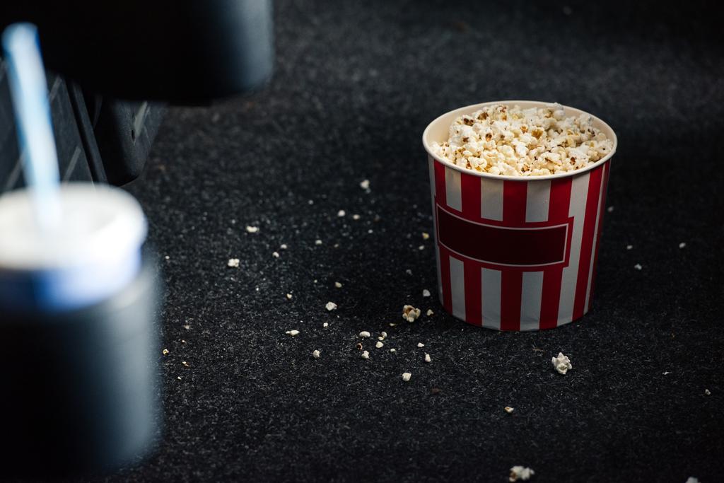 selective focus of stripped red and white paper cup with popcorn on floor - Photo, Image