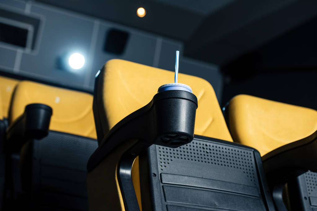 selectieve aandacht van bioscoop stoel met disposable beker met stro in bekerhouder - Foto, afbeelding