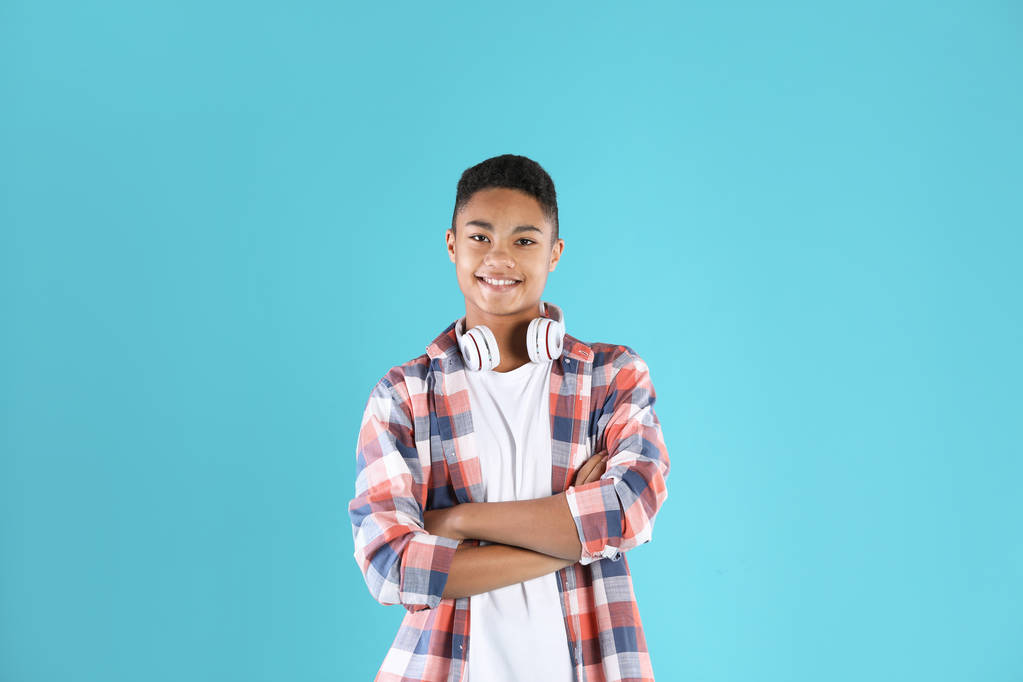 Portrait of African-American teenage boy with headphones on color background - Photo, Image