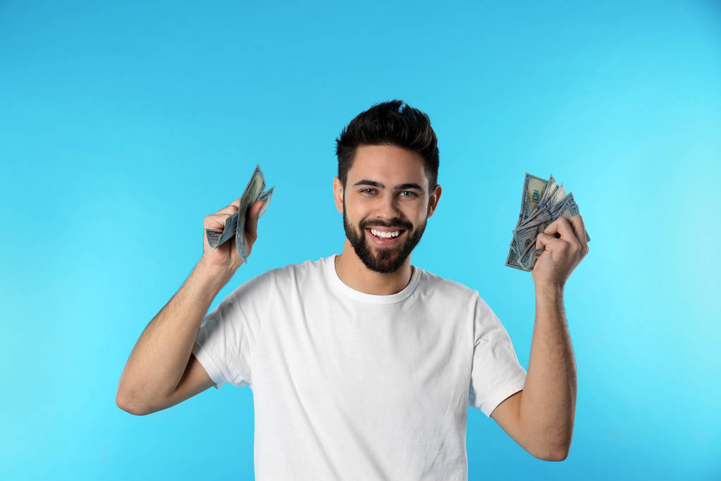 Retrato de jovem feliz com dinheiro em fundo de cor
 - Foto, Imagem