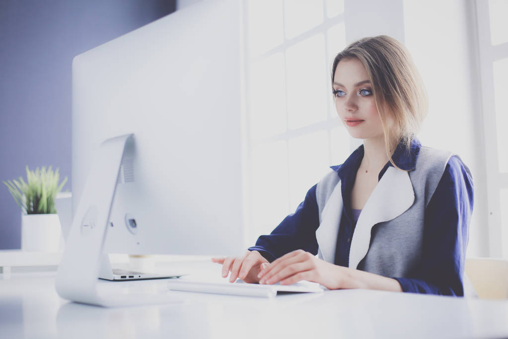 Молодая уверенная в себе деловая женщина, работающая за столом офиса и печатающая с ноутбуком - Фото, изображение