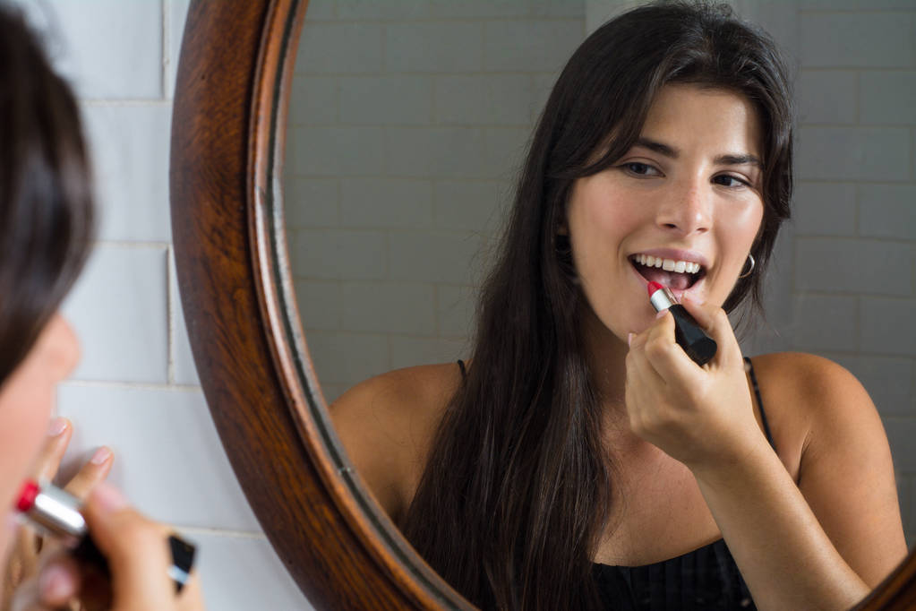 Vrouw toepassen van rode lippenstift in badkamer. - Foto, afbeelding