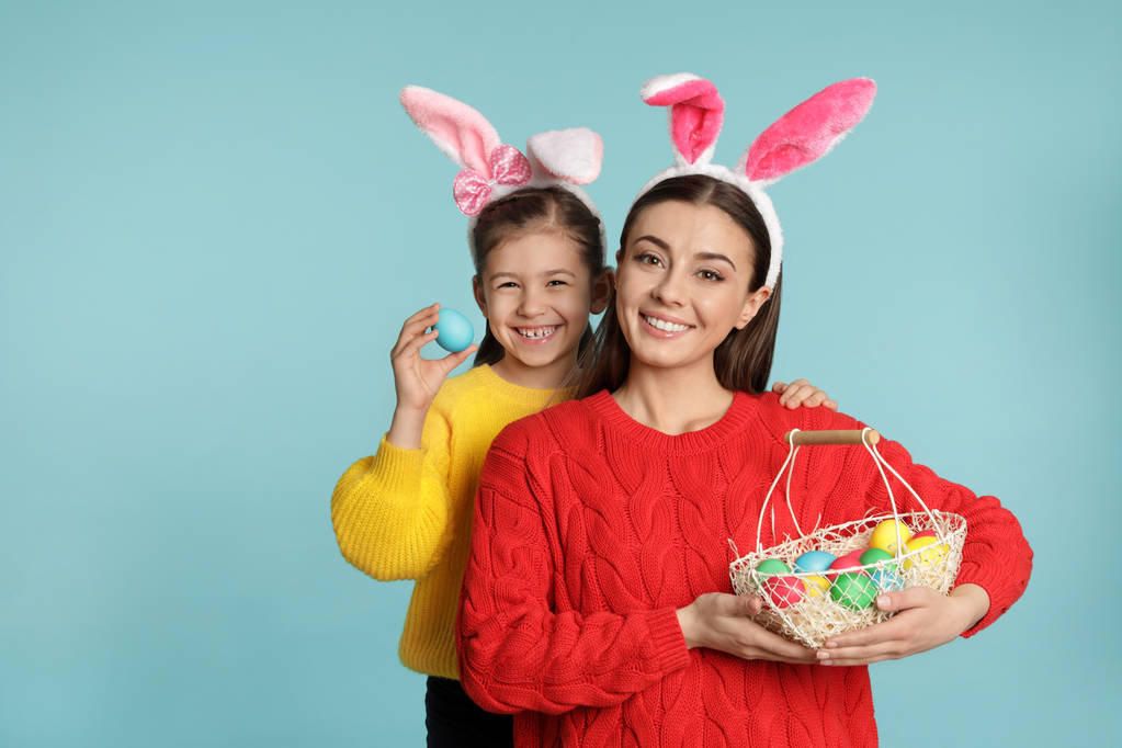 Mère et fille dans les oreilles de lapin bandeaux avec des œufs de Pâques sur fond de couleur
 - Photo, image