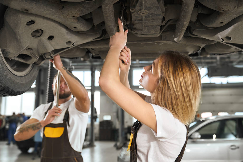 Женщина и мужчина механики ремонт шасси автомобиля
. - Фото, изображение