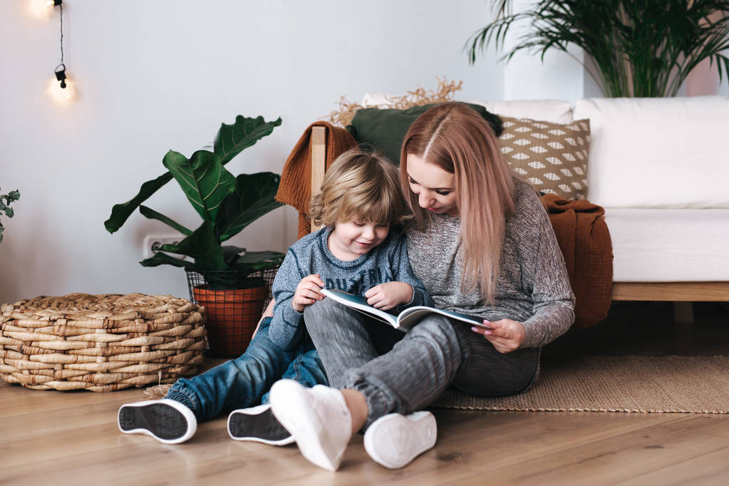 Mother and son sitting and reading book together at home - Photo, Image