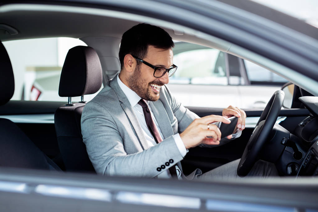 Businessman is choosing a new vehicle in car dealership and making photo on a smartphone - Photo, Image