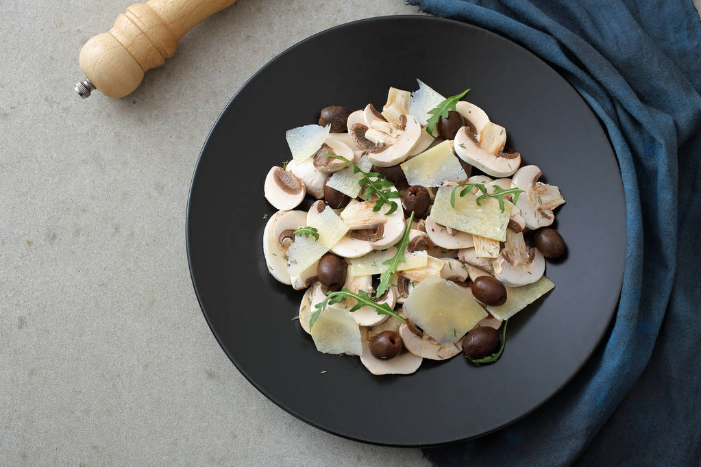 Pilzsalat mit Rucola und Parmesan und Oliven auf Teller  - Foto, Bild