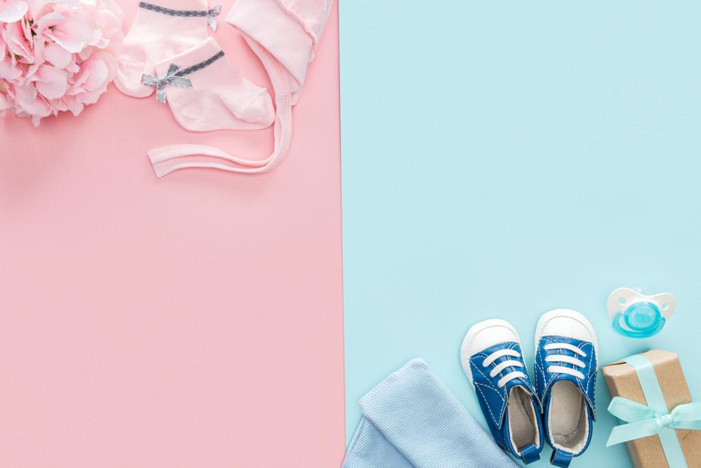 Draufsicht Schnuller, Geschenk, Hut, Mütze, Turnschuhe, Socken, Strauß auf rosa und blauem Hintergrund  - Foto, Bild