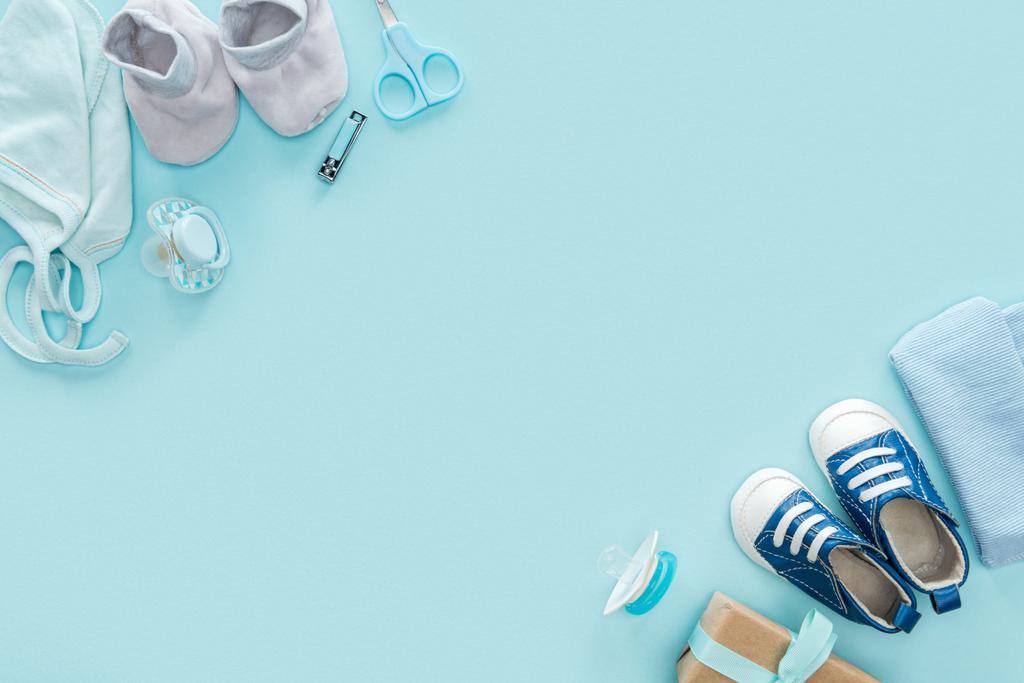 top view of scissors, pacifiers, gift, sneakers, bonnet, booties, hat on blue background  - Photo, Image