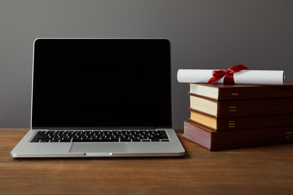 Notebook s prázdnou obrazovkou, knihami a diplomem na dřevěné ploše izolované na šedé - Fotografie, Obrázek