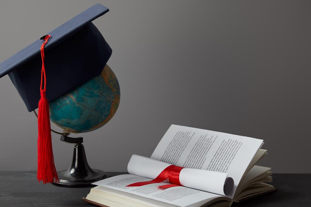 Globe, academic cap, diploma and open book on grey - Photo, Image
