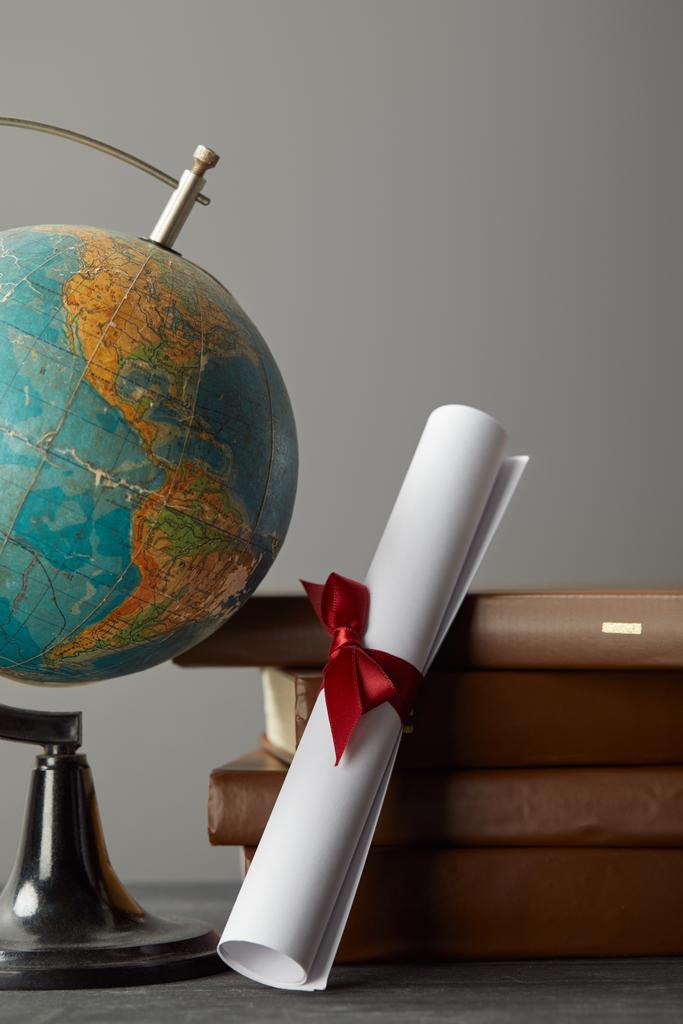 Libros marrones, globo y diploma con cinta roja en gris
 - Foto, Imagen
