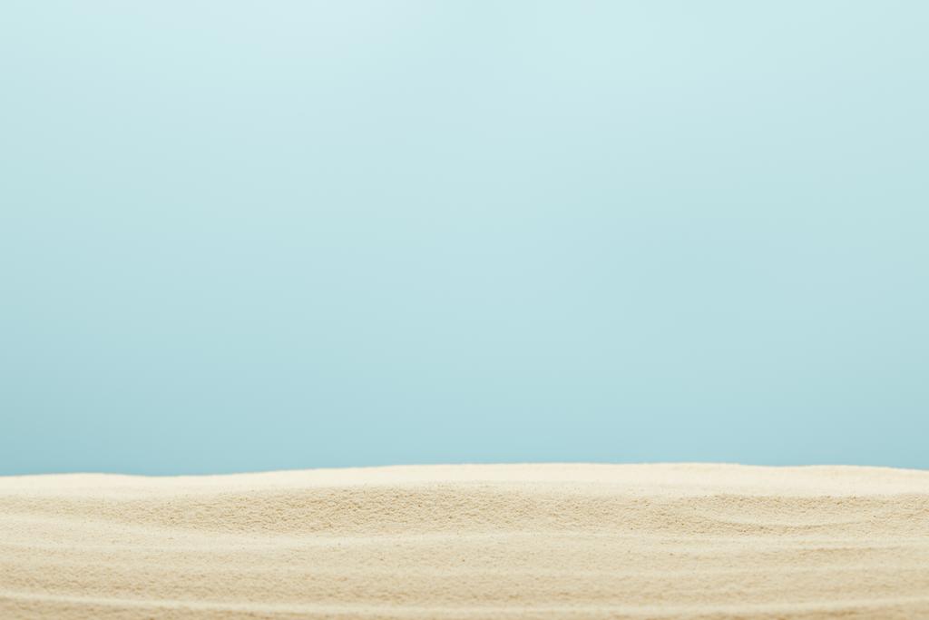 foco seletivo de praia de areia dourada e texturizada isolada em azul
 - Foto, Imagem