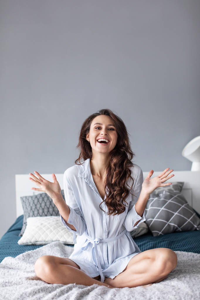 Привлекательная молодая женщина, улыбающаяся на кровати дома
. - Фото, изображение
