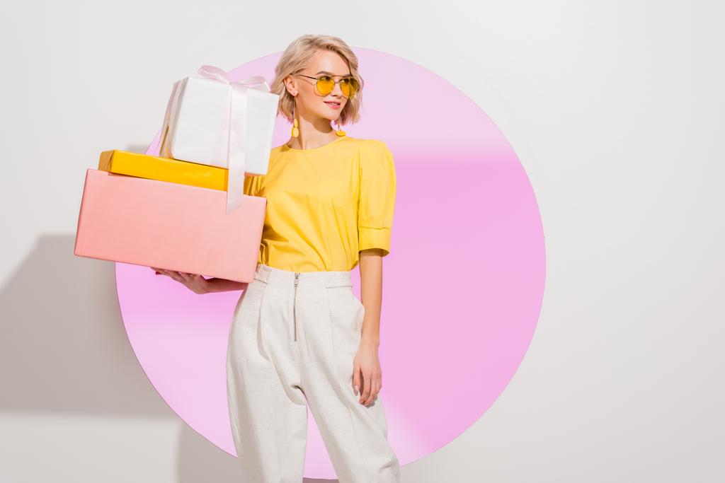 beautiful stylish girl holding gift boxes on white with pink circle and copy space - Photo, Image
