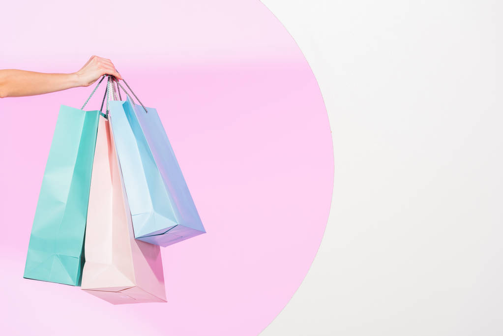 przycięte widok młodej kobiety gospodarstwa kolorowe torby na zakupy na białym z różowym kółkiem - Zdjęcie, obraz