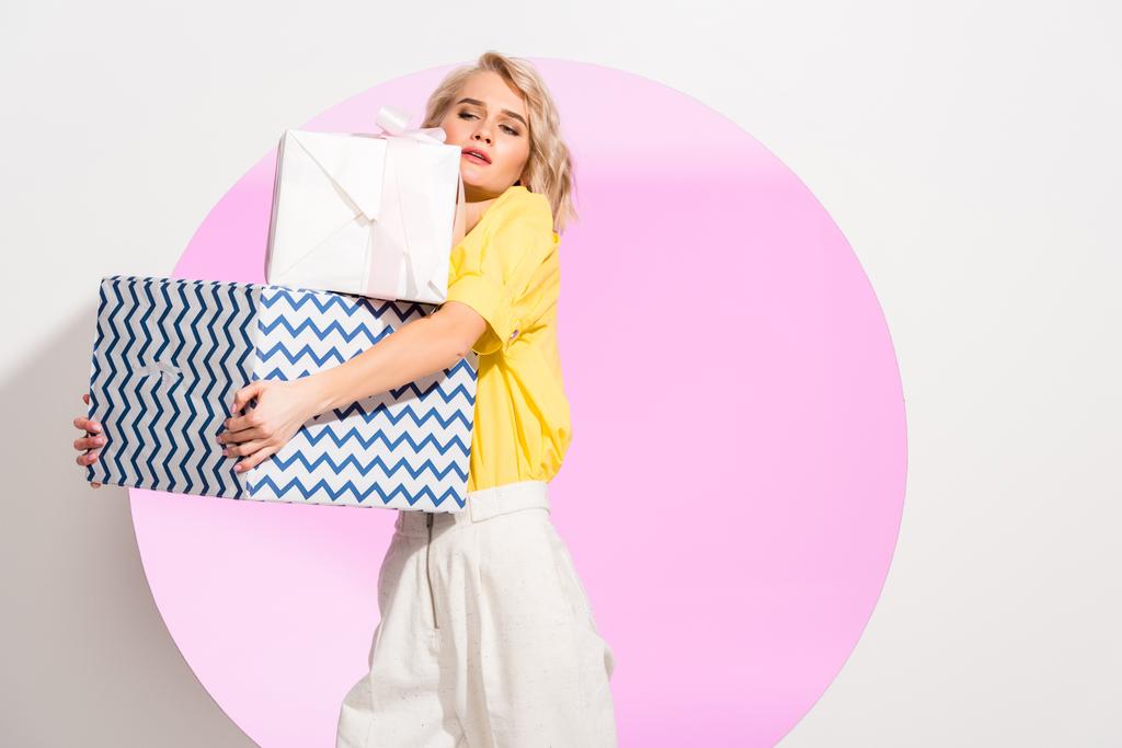 gyönyörű divatos lány gazdaság ajándékdobozokat, fehér, rózsaszín kör és a másolási tér - Fotó, kép