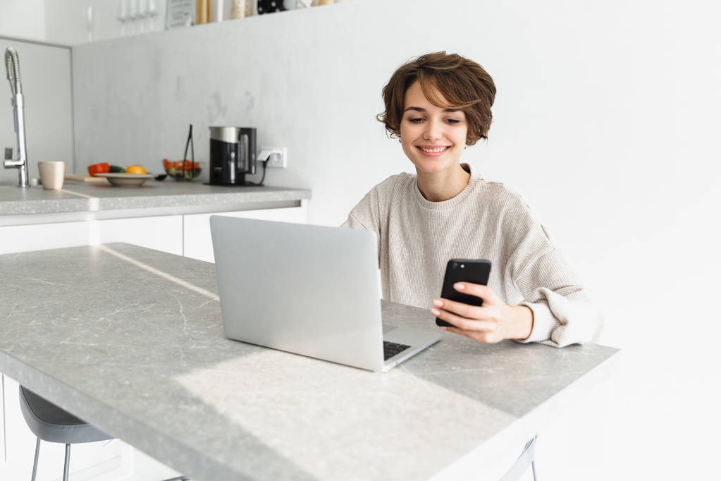 Sonriente joven mujer que trabaja en el ordenador portátil
 - Foto, Imagen