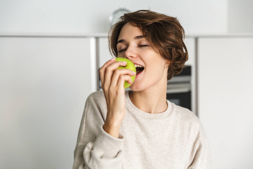 jeune femme souriante tenant pomme verte - Photo, image