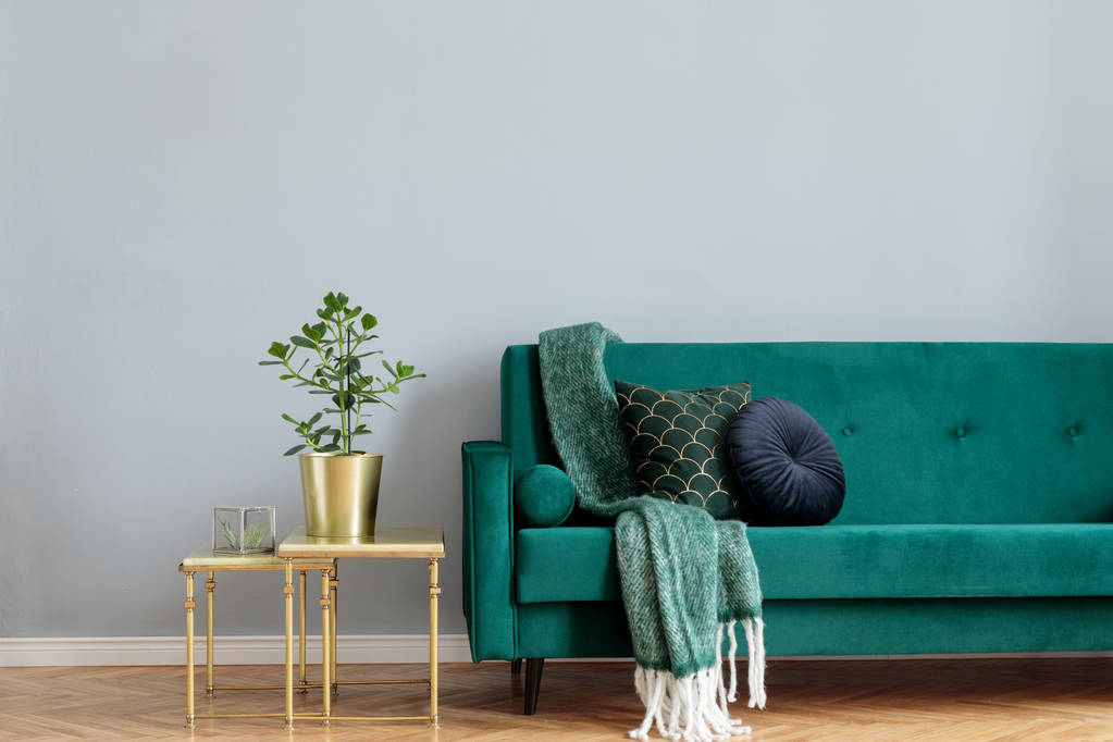 Стильный зеленый велюровый диван, украшенный подушками и журнальным столиком
 - Фото, изображение
